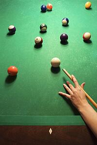 Woman's hand preparing to hit pool ball while playing billiards.