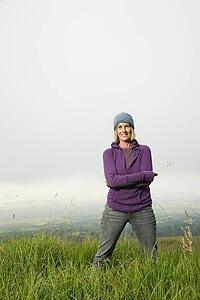 Middle-aged Caucasian woman smiling standing alone in field.