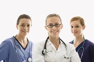 Portrait of smiling Caucasian women medical healthcare workers in uniforms against white background.