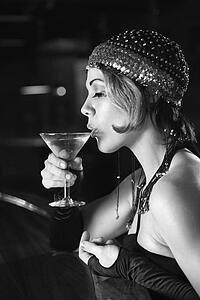Caucasian prime adult retro female sitting at bar drinking martini.