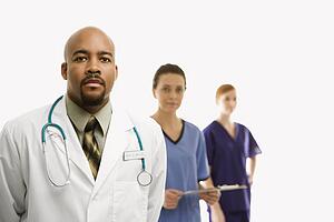 Portrait of African-American man and Caucasian women medical healthcare workers in uniforms standing against white background.
