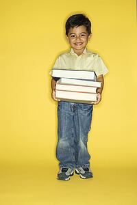 Filipino male child holding stack of books.