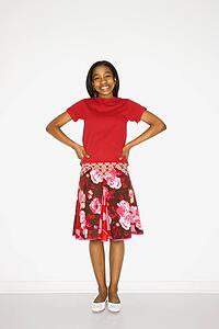 Portrait of African-American teen girl standing with hands on her hips against white background. 