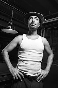 Caucasian prime adult retro male standing with hands on hips in front of pool table.