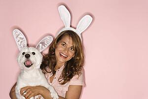 Caucasian prime adult female and white terrier dog wearing rabbit ears.