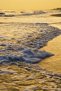 Waves lapping on beach at sunset.