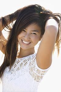 Portrait of young Asian female holding hair up behind her back.