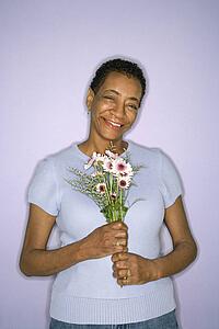 African American mature adult female holding flowers.