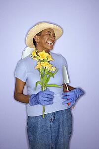 African American mature adult female with hand shovel and flowers.