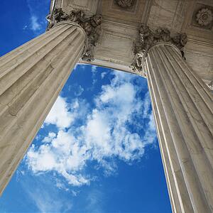 Low angle view looking up at blue sky with clouds and columns of Supreme Court building in Washington D. C.