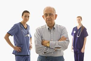 Elderly Caucasian male in foreground with two Caucasian females in the background.