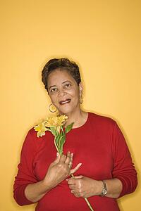 African American mature adult female holding flowers.