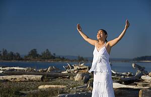 A young woman with arms raised on the beach