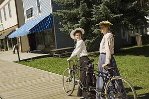 Two women with a vintage bicycle built for two