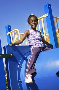 Little girl sitting atop playground equipment