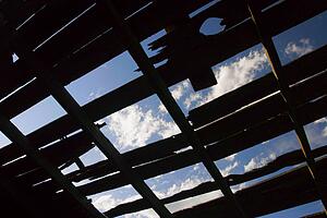 Blue sky though a tattered rooftop