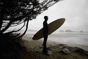Surfer observing water from the beach
