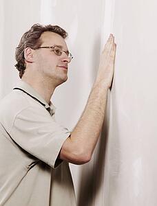 Man checking the smoothness of a wall
