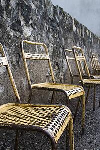 Old metal chairs along a stone wall