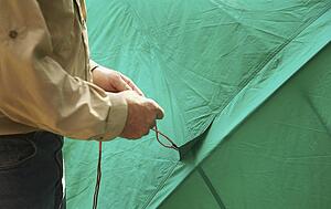 Man holding the rope to a tent