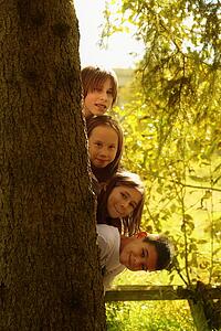 Kids hiding behind tree trunk