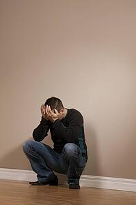 Man crouching with hands over face