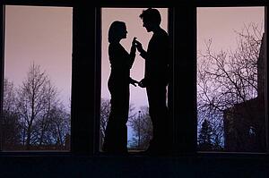 Silhouette of couple facing each other and touching hands