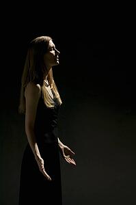 Woman's profile with eyes closed and hands raised