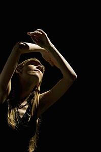 Woman looking up with arms raised over head