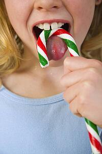Young girl licking candy cane 