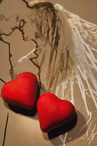 Two red hearts on sketch of wedding couple