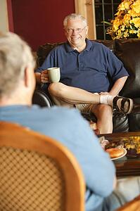 Senior man sitting and visiting with other senior man