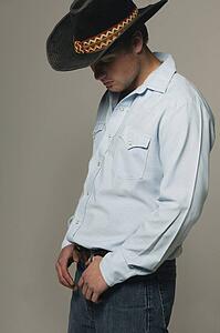 Cowboy looking down with thumbs in belt loops