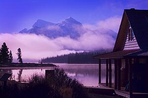 Cabin boathouse and foggy sunrise over mountain lake 