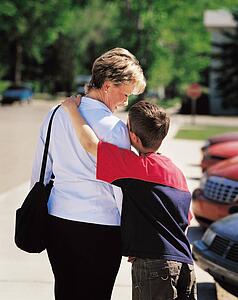 Mother and son in parking lot with son's arm around mother's shoulder