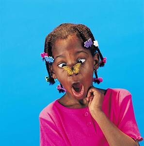 African little girl with butterfly barrettes and a butterfly on her nose looking surprised