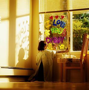 Girl painting the window with "I love you Daddy"