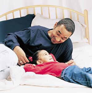 Father and little girl talking on a bed
