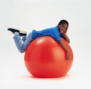 Young boy laying on large red ball