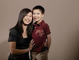 A mother with her arm around son's waist, smiling