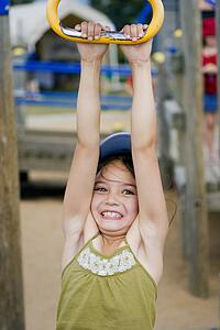 Girl hanging from playground ride 