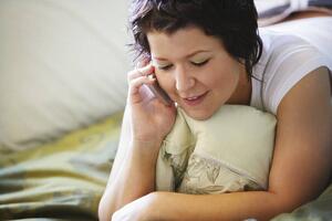 Woman using mobile phone on bed