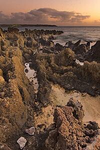 Volcanic rocks on beach and clouds on the horizon