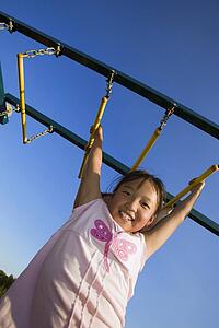A young girl hanging from bar