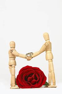 Two mannequins shaking hands with wedding ring and rose