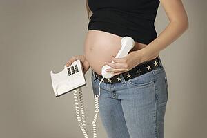 A pregnant woman holding phone to belly