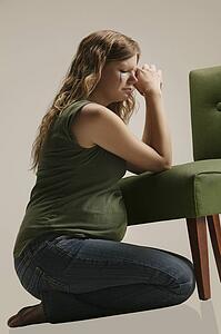 Side view of a pensive pregnant woman sitting by chair