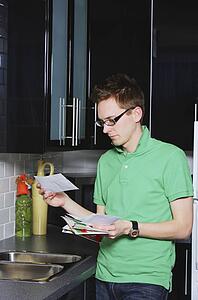 A man reading envelope in the kitchen
