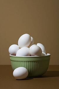 Closeup of white eggs in green bowl 