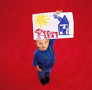 High angle view of a boy showing his painting at camera